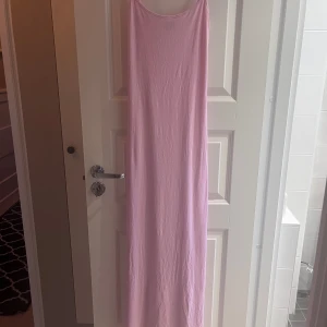 Ljusrosa långklänning Gina Tricot XS - Långklänning i ljusrosa från Gina Tricot. Klänningen har smala axelband och rak passform, perfekt för varma dagar. Tillverkad i mjukt och stretchigt material som känns skönt mot huden.