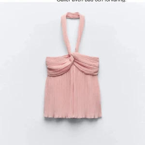 Ljusrosa plisserad halterneck topp - Supersöt ljusrosa halterneck topp med plisserat tyg och twistad detalj framtill. Toppen har en luftig och flowy känsla, perfekt för varma dagar eller när du vill sticka ut lite extra. Snygg att styla med jeans eller kjol.