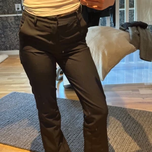 Svarta kostymbyxor från BikBok - Säljer ett par svarta kostymbyxor från BikBok i storlek 36. Byxorna är högmidjade med raka ben och har klassiska fickor fram samt hällor för bälte. Snygg passform som sitter tajt över höfterna och släpper vid benen. Perfekta till en stilren look.