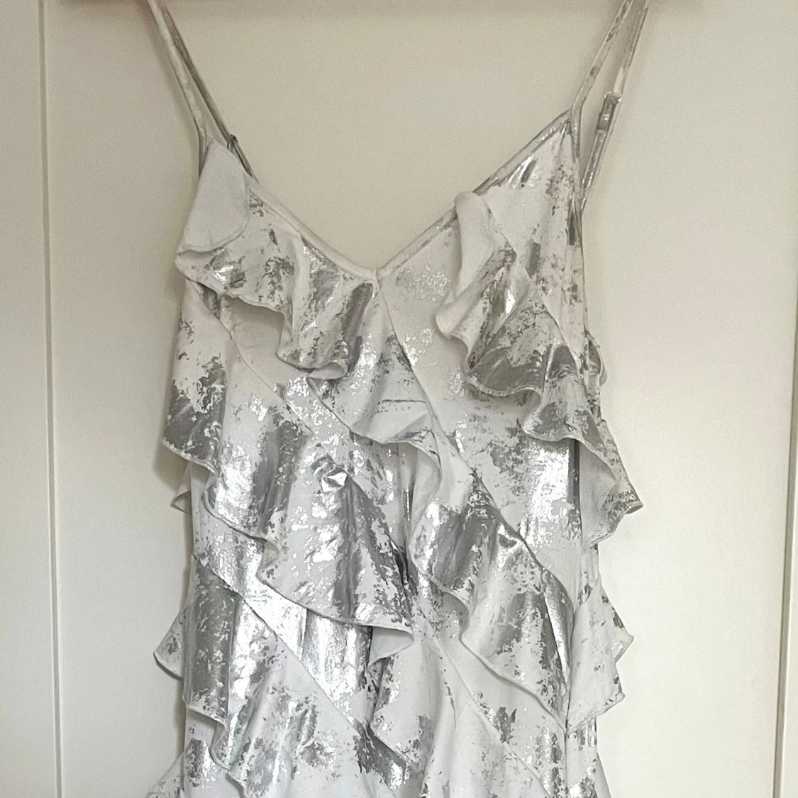 Glittrig silvervit volangklänning