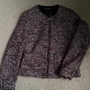 Rutig jacka från Esprit med dragkedja - Snygg rutig jacka från Esprit i mörka toner av vinrött, grått och vitt. Jackan har rak passform, dragkedja framtill och på ärmarna samt två fickor. Materialet är grovt vävt. Pris kan diskuteras