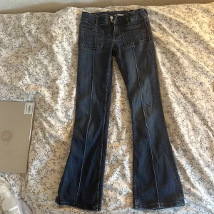 Blå bootcut jeans från Gina Tricot - Snygga blå jeans från Gina Tricot i storlek 152. Modellen har bootcut-ben, stora framfickor och klassisk jeanslook. Perfekta för dig som gillar en retro vibe och vill ha ett par bekväma och trendiga byxor.