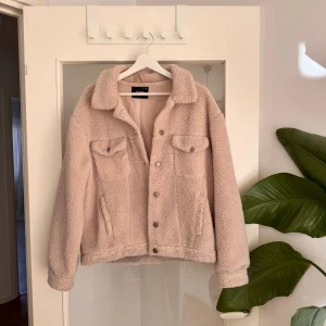 Beige teddyjacka från Soya - Supermjuk och fluffig teddyjacka i beige från Soya. Jackan har klassisk krage, tryckknappar framtill och två bröstfickor med lock. Använd några gånger men är i väldigt bra skick