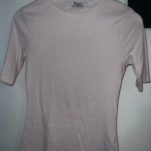 Ljusrosa ribbad topp från NA-KD - Säljer en ljusrosa ribbad topp från NA-KD med rund halsringning och korta ärmar. Enkel och stilren modell som passar perfekt till vardags. Materialet är mjukt och stretchigt för en bekväm passform.