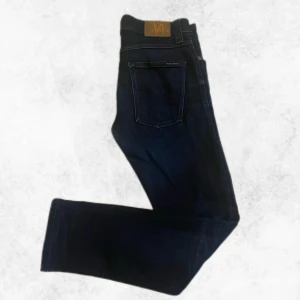 Nudie Jeans Grim Tim Navy Thunder - Mörkblå jeans från Nudie Jeans, modell Grim Tim i färgen Navy Thunder. Tillverkade av 99% ekologisk bomull och 1% elastan för en bekväm passform. Klassisk femficksdesign och normal passning.