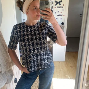 Svartvit mönstrad topp  - Säljer en svartvit topp med rutigt mönster. Toppen har rund halsringning och korta ärmar. Perfekt till jeans eller kjol för en stilren look.