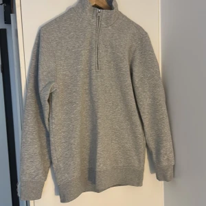 Grå halvzip tröja från MNG - Säljer en grå halvzip tröja från MNG i regular fit. Tröjan har lång ärm, hög krage och dragkedja framtill. Mjuk insida och ribbade muddar vid ärmslut och nederkant. Perfekt för lager-på-lager och enkel att matcha.