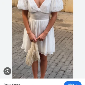 Vit kortklänning med puffärmar - Superfin vit kortklänning från Gina med v-ringning och knytning bak med rosett. Helt ny och helt slutsåld på hemsidan! Nypris 700kr