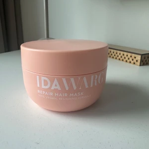 Repair Hair Mask från Ida Warg - En ljusrosa burk med Repair Hair Mask från Ida Warg. Hårmasken är 100% vegansk och har en återuppbyggande formula. Innehåller bland annat sheasmör, solrosfröolja och parfym. Volym: 300 ml.