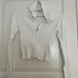 Vit ribbad kofta från NA-KD  - Säljer en vit ribbad kofta från NA-KD  i storlek XS. Tröjan har lång ärm, dragkedja framtill och en bred krage som ger en snygg och modern look. Man kan ändra på dragkedjan så man bestämmer hur den ska sitta både nedifrån och uppifrån💕