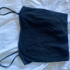Svart linnetopp från H&M Divided - Säljer en enkel svart linnetopp från H&M Divided. Toppen har smala axelband och är ärmlös, perfekt för varma dagar eller som lager under andra plagg. Klassisk och stilren design som passar till mycket.