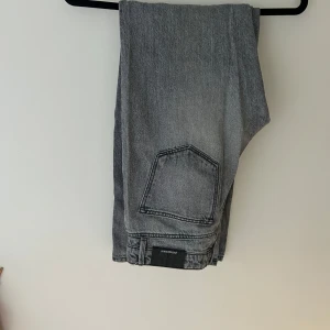 Grå jeans från Stradivarius - Säljer ett par grå jeans från Stradivarius med klassisk femficksdesign och dragkedja. Jeansen har råa, fransiga benslut för en trendig look. Perfekta till vardags och lätta att matcha med olika stilar.