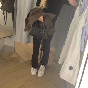 Svart väska med ditaljer  - Såå fin väska med ditaljer! Perfekt stolek för det viktigaste och enkel att matcha till olika outfits. Knappt andvänd då den är andvänd cirka 2-3 gånger, inga defekter! Hör av er om ni har fler frågor💕💕 Höjd: ca 14 cm, bred: ca 20 cm💕 (följer med band till väskan).