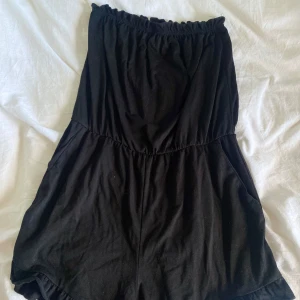 Svart axelbandslös body från New yorker - Svart axelbandslös body från New yorker i mjuk bomull. Bodyn har resår upptill och vid midjan för en bekväm passform. Perfekt för varma dagar och enkel att styla med accessoarer.