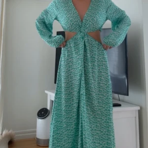 Grön mönstrad långklänning med knut framtill - Säljer denna jättesnygga gröna långklänning med v-rigning och cut-out, samt en slits nertill då jag har två💚den (som jag säljer) är endast testad, men utan prislapp!! Pris kan diskuteras, alternativt, kan tänka mig byta mot en annan vara!🥰