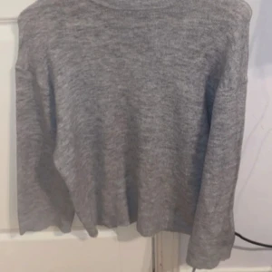 Grå stickad tröja - Mysig grå stickad tröja med lång ärm och rund hals. Perfekt för lager-på-lager och passar till både jeans och kjol. Enkel och stilren design som funkar till många olika outfits.