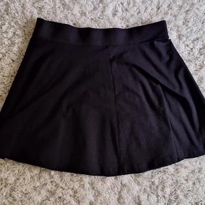Svart A-line kjol - Svart A-line kjol från H&M Divided. Staple, fungerar med många olika saker och olika stilar! Mjukt material med ganska mycket stretch i midjan