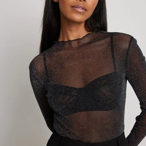 Glitttig tröja NA-KD - Skitsnygg festlig glittrig genomskinlig tröja i svart från NA-KD, strl XS, aldrig använd, helt ny, nyskick, (endast prövad) säljer pga kmr ej till användning OBS! Braletten jag har under ingår ej