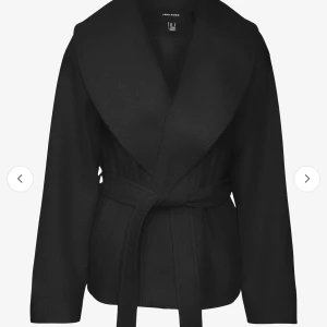 Svart kappa med bälte från Vero Moda - Snygg svart kappa från Vero Moda med bred krage och knytskärp i midjan. Jackan har lång ärm och en klassisk, stilren look som passar perfekt till höst och vår. Enkel att matcha med olika outfits.
