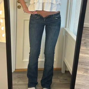 Lågmidjade utsvängda jeans  - Jätte fina jeans från Wrangler! De är för små för mig så går därför inte att stänga i midjan. Storleken är W25 L34 och måtten är:  Innerben: 85 cm, midja rakt över 36 cm Kom privat för fler mått eller frågor🥰