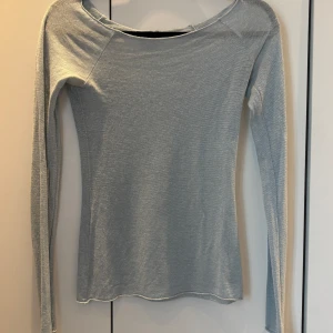 Ljusblå glittrig långärmad topp från Design by Si - Säljer en ljusblå långärmad topp från Design by Si. Toppen har en glittrig finish och är figurnära med rund halsringning. Perfekt att styla till olika outfits för en extra touch av glitter.