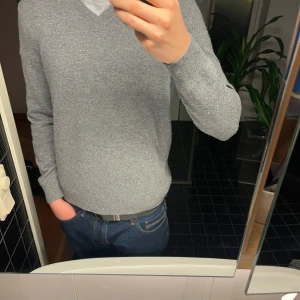 Grå kashmir tröja - Säljer en stilren grå stickad kashmir tröja från Brooks Brothers med v-ringning. Perfekt för kyligare dagar och passar bra till både jeans och chinos. Tröjan har långa ärmar och en klassisk design som aldrig går ur tiden.