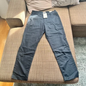 Svarta byxor från These Glory Days - Snygga svarta byxor från These Glory Days i regular fit. Byxorna har en klassisk design med knapp och dragkedja i midjan. Perfekta för en stilren look. Kan inte riktigt storlekarna på denna modell så jag kan iaf säga att 46 passar inte mig som är 187