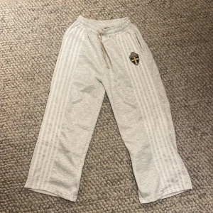 Grå mjukisbyxor med broderad logga - Snygga grå mjukisbyxor med en broderad logga på sidan. Byxorna har en bekväm passform med elastisk midja och snörning. Baggy men ganska små