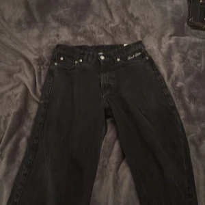 Svarta jeans från Sweet Sktbs - Snygga svarta jeans från Sweet Sktbs med broderad logga på fickan. De har en klassisk femficksdesign och knappgylf. Perfekta för en stilren look.