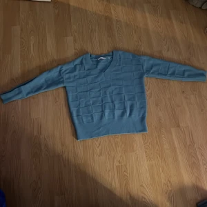 Blå stickad tröja från Yaya - Säljer en snygg blå stickad tröja från Yaya. Tröjan har en v-ringad design och ett diskret rutmönster. Perfekt för kyligare dagar. Passar bra till jeans eller kjol. 💙