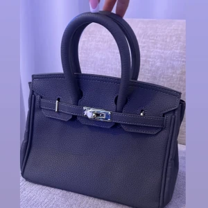 Svart handväska med metallspänne - Elegant svart handväska med ett stilrent metallspänne framtill. 