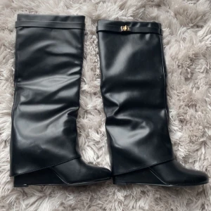 Svarta stövlar med kilklack - Super snygga svarta stövlar i skinn med kilklack och dekorativt guldigt spänne upptill. Använt de 1 gång, har vanligtvis storlek 39/40 men dessa sitter bra som är i storlek 41