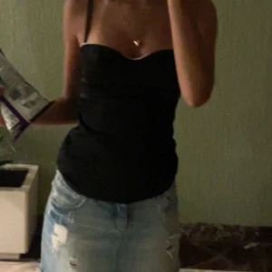 Svart korsettopp - Snygg svart korsettopp med justerbara axelband. Toppen har en elegant och figurnära design som framhäver siluetten. Perfekt för en stilren look.