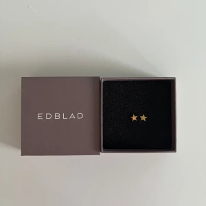 Guldstjärna örhängen från Edblad - Snygga och stilrena örhängen i form av små guldstjärnor från Edblad. Perfekta för att ge en subtil men elegant touch till din look. Kommer i originalförpackning. Inga defekter och aldrig använda, då jag endast använder silver örhängen. Nypris: 250kr