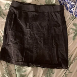 Svart kortkjol - Snygg svart kortkjol i ett enkelt och stilrent snitt. Perfekt för att matcha med olika toppar och accessoarer. Kjolen har en bekväm passform och är lätt att bära till olika tillfällen.