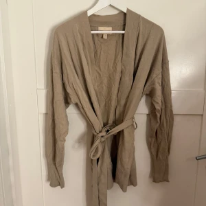 Beige kashmirblandad kofta från H&M - Säljer en elegant beige kofta från H&M i kashmirblandning. Koftan har långa ärmar och ett knytbälte i midjan. Använd 2 gånger max. Storlek S 💖