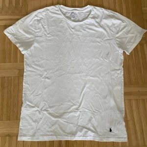 T-shirt från Polo Ralph Lauren - Säljer en klassisk vit t-shirt från Polo Ralph Lauren. Den har en broderad logga i svart på nedre delen. Perfekt för en stilren look. T-shirten har ett minimalt hål på den nedre delen, kolla bilden.