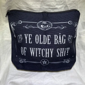 Ny! Svart necessär med text - Ny! Cool svart necessär med texten 'Ye Olde Bag of Witchy Shit' i vitt. Perfekt för att förvara dina magiska tillbehör eller smink. Den har en praktisk dragkedja upptill och är lätt att ta med sig. Kika gärna på mina andra annonser har massor att sälja 🌸