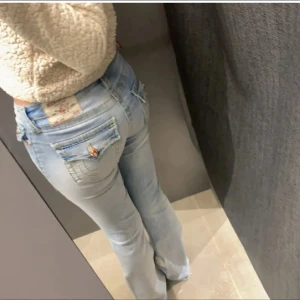 True religion bootcut jeans  - Snygga ljusblå bootcut jeans med låg midja och dekorativa fickor bak. Perfekta för en avslappnad stil. Märkeslappen syns tydligt på baksidan.