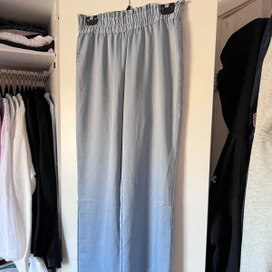 Ljusblå pyjamasbyxor - Snygga ljusblå pyjamasbyxor från Kappahl med elastisk midja för extra komfort. Byxorna har en loose passform, brett resårband i midjan och är perfekta för en avslappnad stil. Tillverkade i ett mjukt och lätt material som ger en skön känsla. 🩵 Önskar du veta exakta mått? Tveka inte att höra av dig!