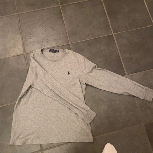 Ralph lauren tröja  - Säljer en stilren grå långärmad tröja från Ralph Lauren. Tröjan har en klassisk rund halsringning och det ikoniska broderade logotypen på bröstet. Nästintill helt nya Raffe tröja perfekt nu till våren. 🤝🏽Tröjan är slim💯Pris kan diskuteras🙌kom med frågor och funderingar!