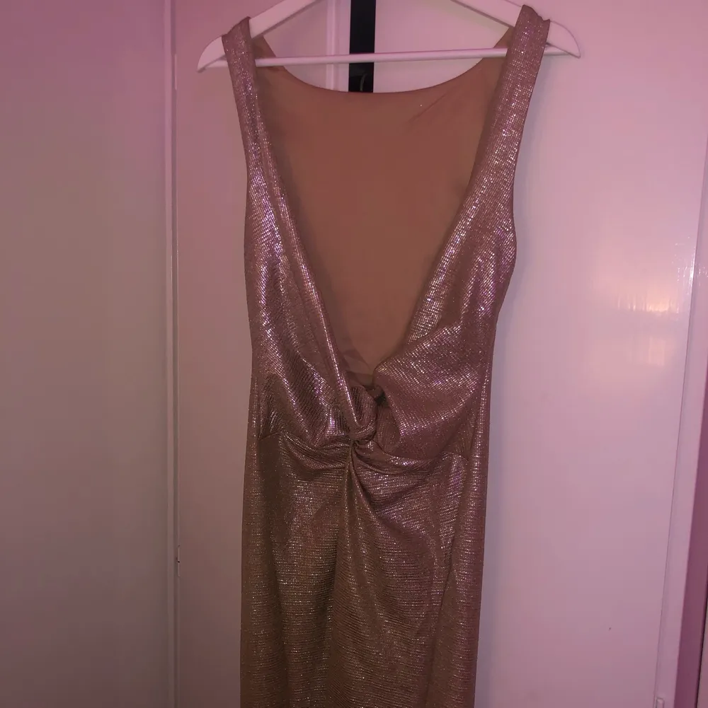 Lång, guldglittrande balklänning med öppen rygg. Klänningen köptes år 2019 och kan därför inte köpas i butik längre, klänningen användes dock bara en gång är därför i nyskick! Otroligt fin att ha på en bal eller liknande tillställningar :) (Nypris: 999 kr). Klänningar.