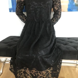 Snygg klänning i spets - Festlig klänning i 80 %viskos och 20 % polyester. Fodrad. Aldrig använd endast provad. Midja: 72 cm Längd mitt bak: 112 cm