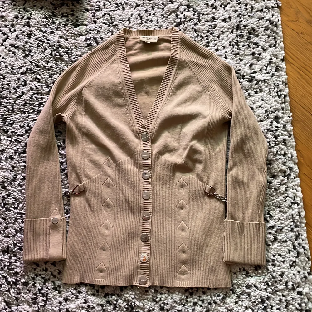 Beige cardigan.  Label size: 2, but is very small (34/xs)  Small damage on one of the buttons  Decorative silver chains on the sides . Tröjor & Koftor.