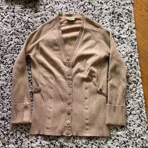 Beige cardigan.  Label size: 2, but is very small (34/xs)  Small damage on one of the buttons  Decorative silver chains on the sides 