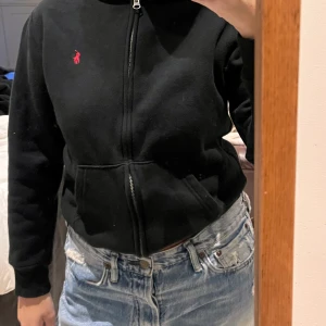 Ralph lauren hoodie  - Svart ralph lauren hoodie med dragkjedja. Storlek 14-16 år men skulle säga att den passar XS i vuxen storlek. Jag brukar ha S och den passar förutom lite kortare i armarna