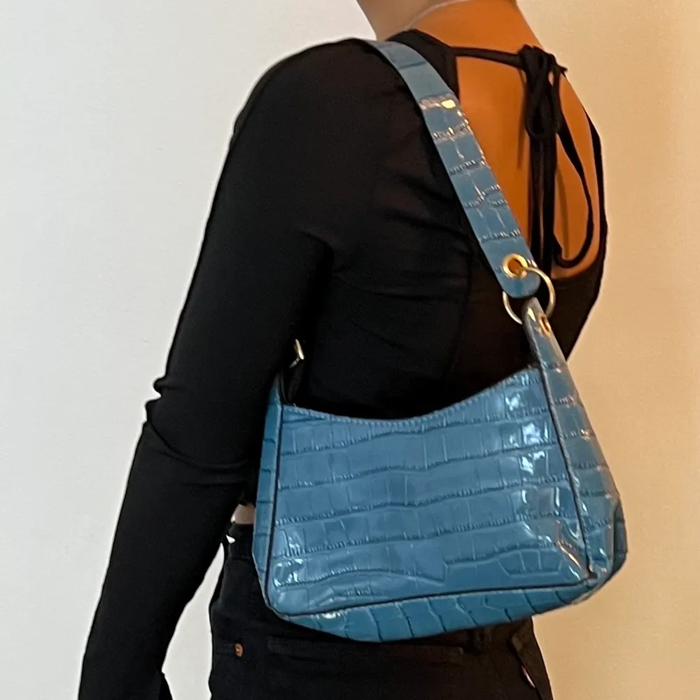 Säljer en söt blå väska!  Väskan är i mörkblå färg med ett glansigt matrial. Säljs pågrund av att jag har för mycket väskor. Köparen står för frakten  (Första bilden visar bäst ljus) . Accessoarer.