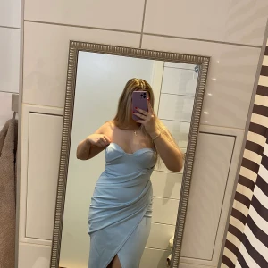 Ljusblå omlottklänning - Använd 2 gånger, sitter som en smäck på kroppen, storlek S. Den är Midi och har en slit , över brösten finns det som ett silikonband som gör att klänningen inte glider ner.