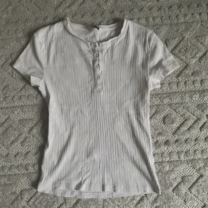 Vit ribbad t-shirt  - Säljer denna ribbade vita tighta t-shirt. Bra skick då den är använd fåtal gånger. (Har en likadan i brun som jag säljer) Skriv om ni har frågor! Pris+frakt 