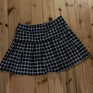Rutig kjol - Rutig kort kjol med shorts under. Den är svart och vit med rosa söm. Bra skick. Djur i hemmet.